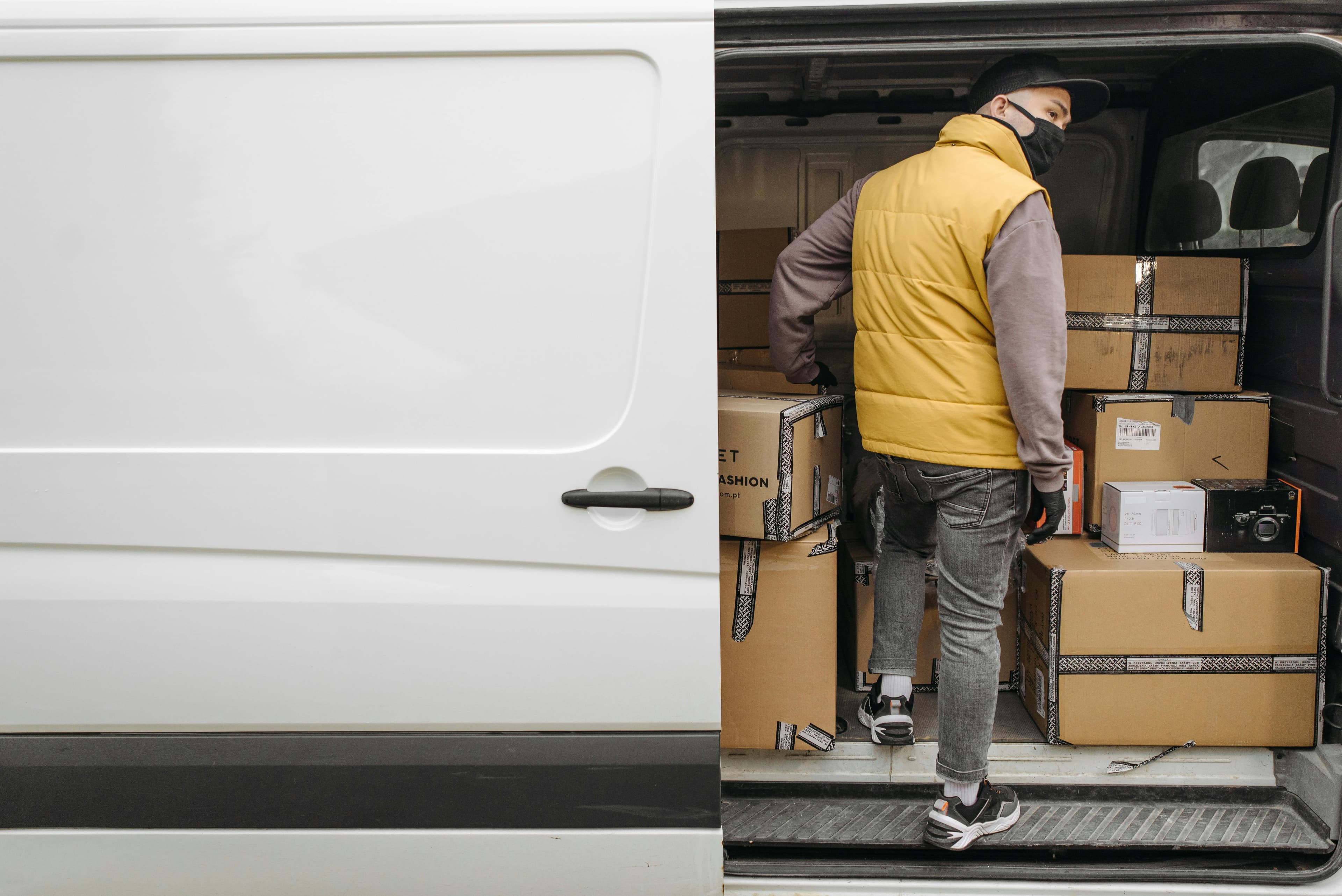 Courier loading boxed parcels into a delivery van
